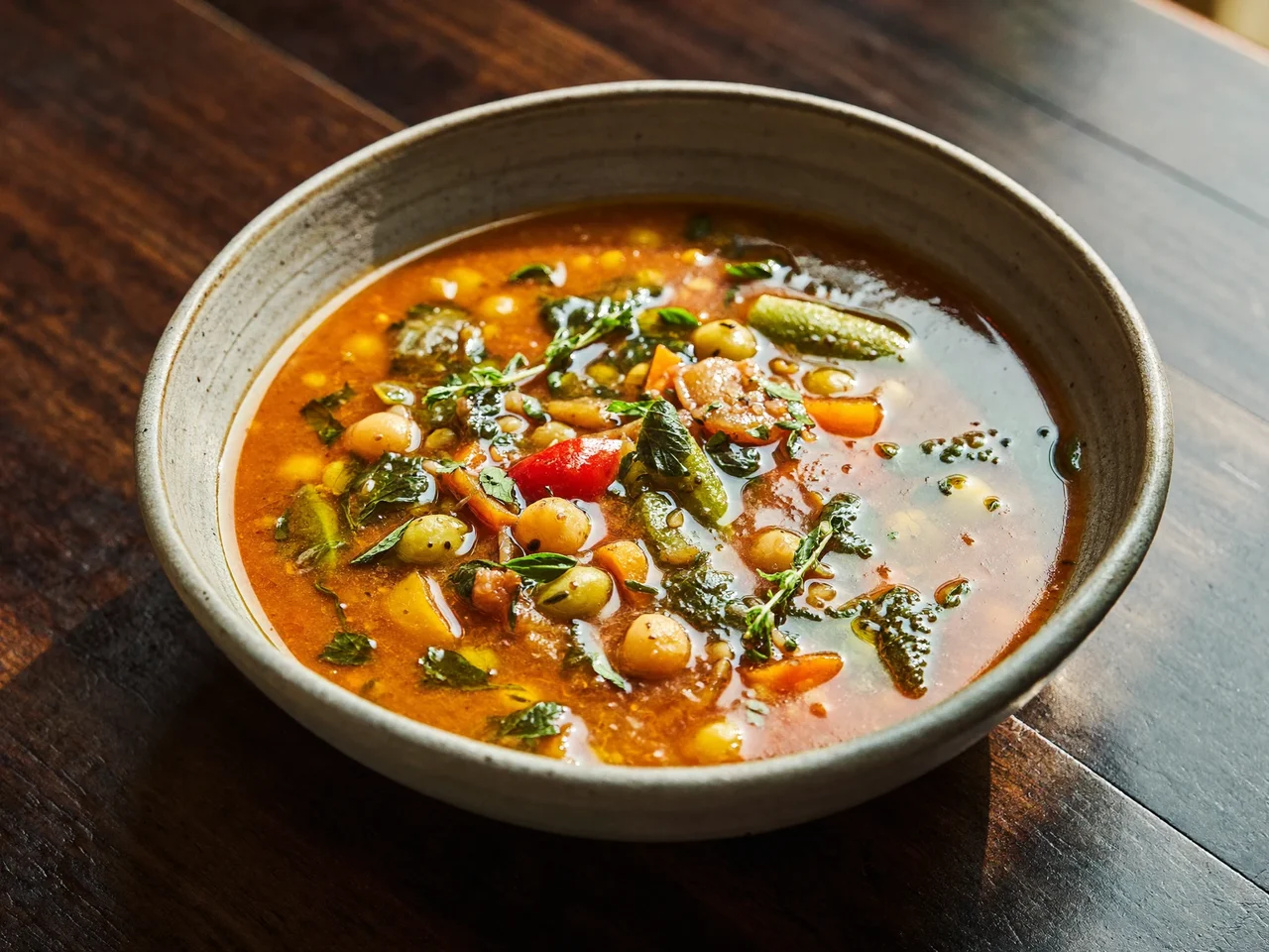 Zuppa mediterranea di verdure e legumi in una ciotola di ceramica con olio a crudo